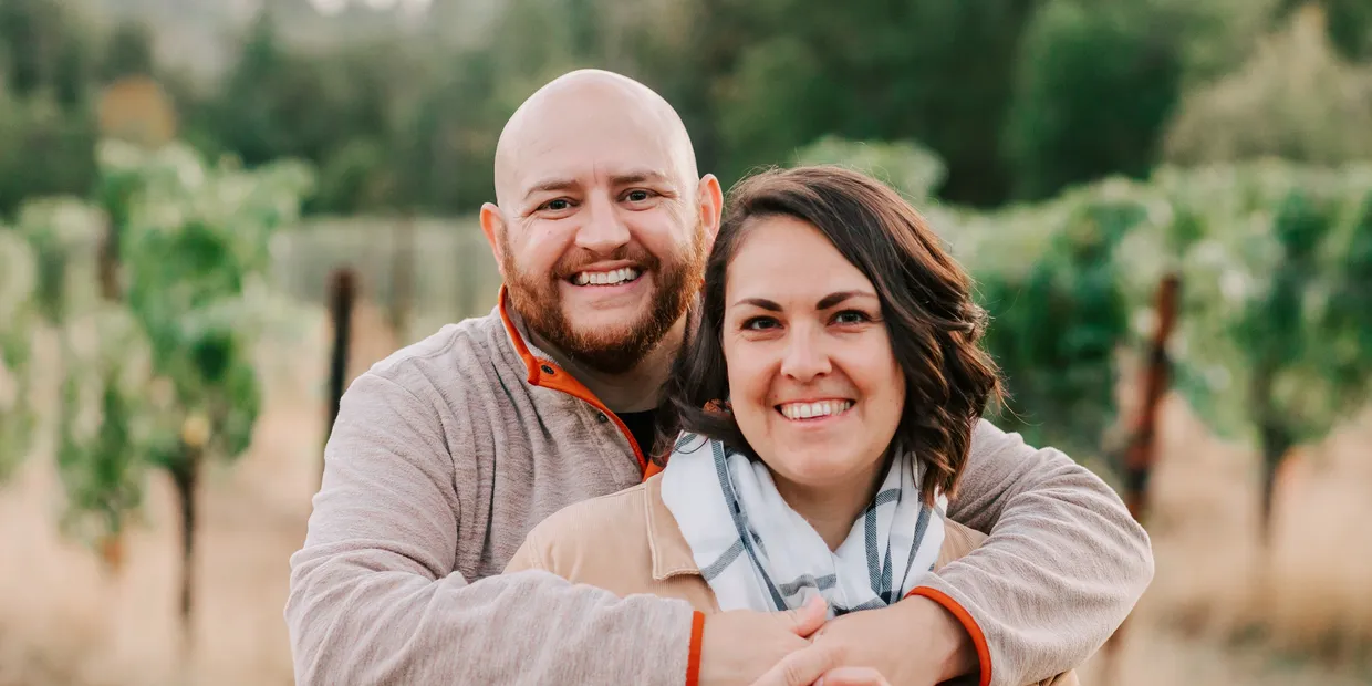 Albert and Joanna, owners of Do Good Cleaning Services, smiling together in a vineyard near Salem, Oregon
